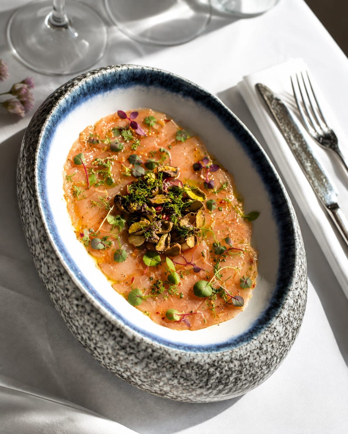 Carpaccio de poisson aux pistaches parsemé de microgreens fraîches dressées à l'assiette